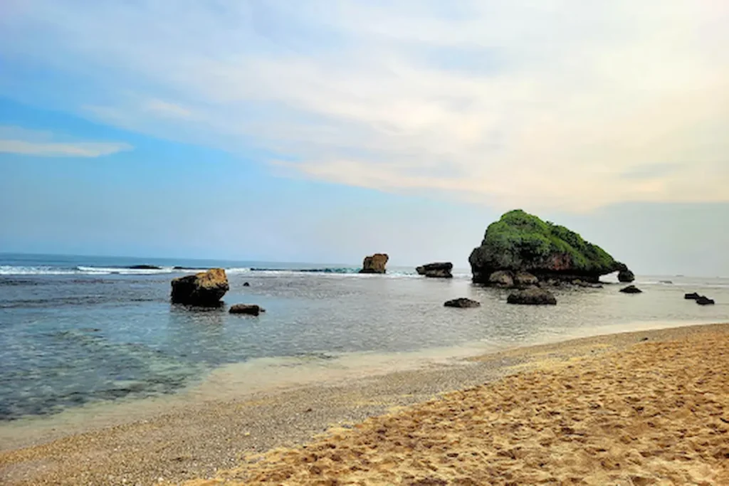 pemandangan pantai dan lau dengan batu besar di tepi pantai